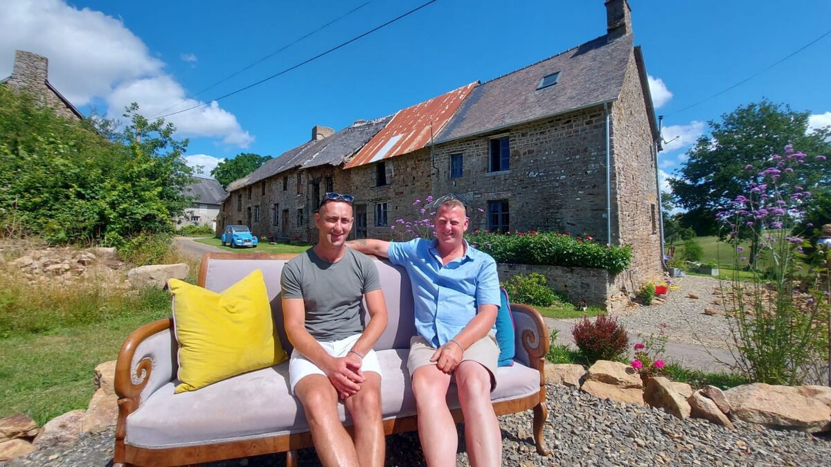 Yip and Paul sitting on a sofa outside the stone cottages of La Buslière